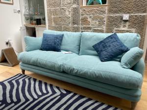 a blue couch with blue pillows in a living room at Large 3 double bedroom period house with parking in Edinburgh