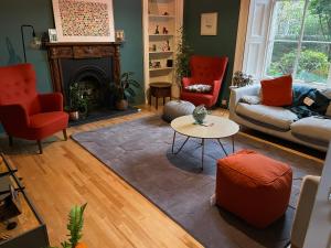 a living room with red chairs and a fireplace at Large 3 double bedroom period house with parking in Edinburgh