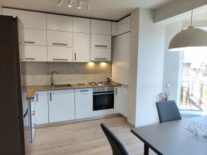 una cocina con armarios blancos y una mesa con sillas. en SWEET HOME - central cozy apartment, en Cluj-Napoca