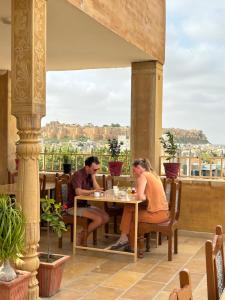 un hombre y una mujer sentados en una mesa en un patio en Hotel Heritage Haveli, en Jaisalmer