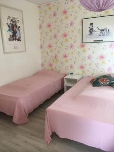 two beds in a room with pink sheets at Charmig Ölandsgård in Köpingsvik