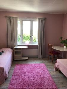 a bedroom with a pink rug and a window at Charmig Ölandsgård in Köpingsvik