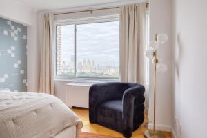 a bedroom with a blue chair in front of a window at UES 3br w balcony doorman nr Central Park NYC-1192 in New York