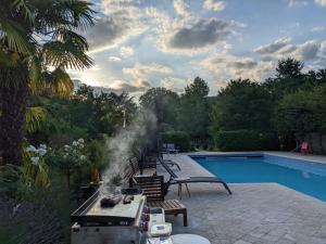a barbecue grill next to a swimming pool at Domaine Chapelle in La Chapelle-la-Reine