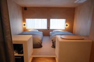 a small room with two beds and two windows at APARTMENTS by Bed and Craft in Inami +25 photos