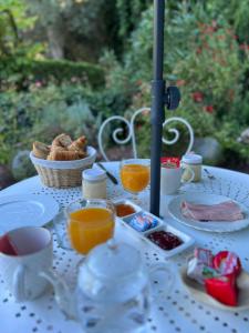 een witte tafel met eten en een mand sinaasappelsap bij Maison Riquet in Castelnaudary
