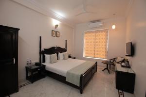 um quarto com uma cama, uma televisão e uma janela em Jai Villa - A Boutique Hotel em Jaipur