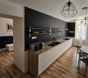 eine Küche mit weißen Schränken und einer schwarzen Wand in der Unterkunft Penzión TIME in Prešov