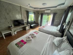 um quarto de hotel com duas camas e uma televisão em ชิดชายชล รีสอร์ท น่าน em Nan