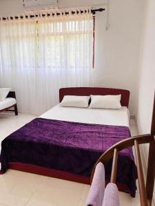 um quarto com uma cama com um cobertor roxo em The Cinnamon Villa Kandy em Kandy