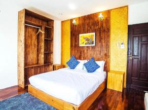 a bedroom with a large white bed with blue pillows at Pai Woodland Resort in Pai