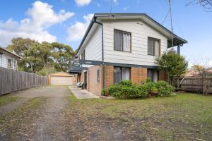 una casa blanca con valla y entrada en INVERLOCH Beach House, en Inverloch