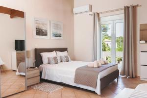 a bedroom with a large white bed and a window at Plakoures Home in Kounoupidhianá