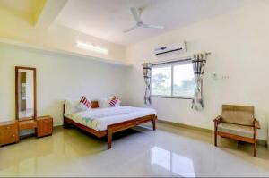 1 dormitorio con cama, ventana y silla en Narmada NATH Homestay, en Rājpīpla