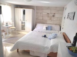 a white bedroom with a bed and a bowl of fruit at Apartmán BRAĆKI CVIJET in Sutivan