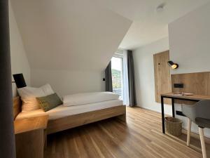 1 dormitorio con 1 cama, escritorio y ventana en Ferienhaus Waldschatz Baiersbronn, en Baiersbronn