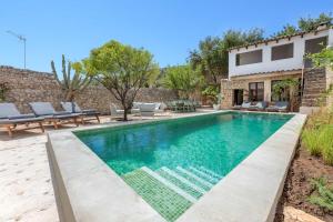 a swimming pool with chairs and a house at El Convento de Biniamar in Selva