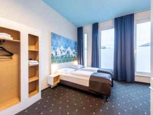 a bedroom with a bed and a large window at B&B Hotel Rosenheim in Rosenheim