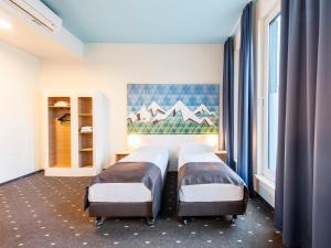 dwa łóżka w pokoju z dwoma oknami w obiekcie B&B Hotel Rosenheim w mieście Rosenheim
