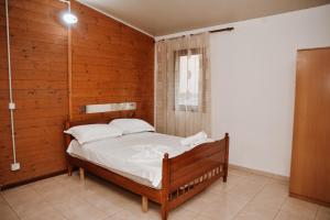 a bedroom with a bed with a wooden wall at Village of Peace - House 40 in Shkodër