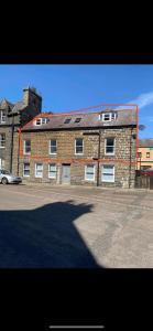 a large brick building with a car parked in front of it at 3 Bedroom Townhouse on NC500, Wick, Highland in Wick
