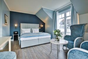 a bedroom with a bed and two chairs and a table at Sylthotel Raffelhüschen Garni in Westerland (Sylt)
