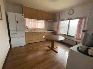 a kitchen with a table and a white refrigerator at Kien in Sapporo