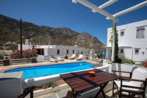 een patio met een tafel en stoelen en een zwembad bij Mosha Pension in Kamarai