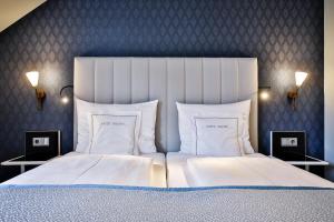 1 dormitorio con 1 cama grande con sábanas y almohadas blancas en Sylthotel Raffelhüschen Garni, en Westerland