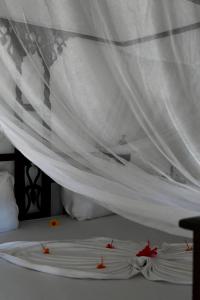 Una cama blanca con flores rojas. en Amka House, en Jambiani