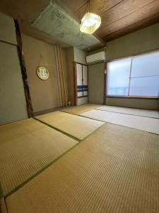 een lege kamer met een groot raam en een klok bij 素泊まり民宿とみや in Oshima