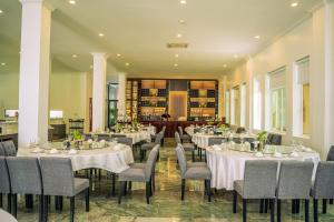 白马市Sangkahak Mith Hotel的摆放着白色桌椅的餐厅