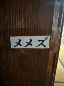 a sign on the side of a wooden door at 素泊まり民宿とみや in Oshima