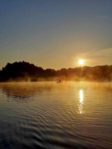 a sunrise on a lake with a boat in the water at WW Wzdłuż Wisły in Józefów