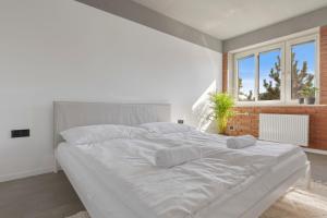 a white bedroom with a large white bed with two pillows at Sofia Apartment - With parking in Bratislava