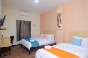 ein Hotelzimmer mit 2 Betten und einem Schreibtisch in der Unterkunft Sans Hotel City Park Medoho Semarang in Alastuwo