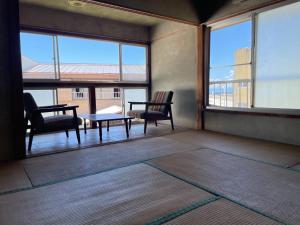 素泊まり民宿とみや في Oshima: غرفة بها كرسيين وطاولة ونوافذ