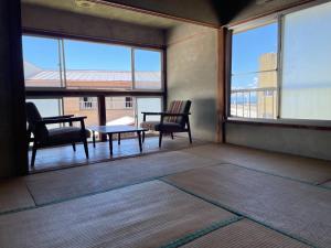 a room with two chairs and a table and windows at 素泊まり民宿とみや 全部屋個室 伊豆大島 in Oshima