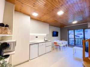 a kitchen with white cabinets and a table with a dining room at Lujoso Ático Dúplex En Valle De Incles - Parking Gratis in Canillo