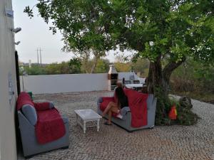 a woman sitting on a couch under a tree at Casa Madeira in Silves +2 photos
