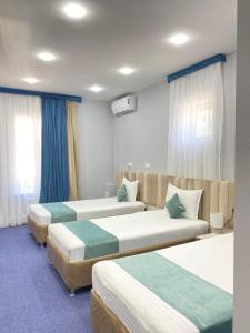 a hotel room with three beds in it at Aperol Hotel in Tashkent
