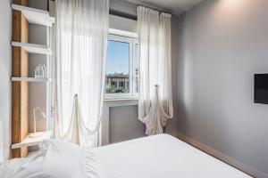 1 dormitorio con cama blanca y ventana en Ferrini Home - Suites, en Catania