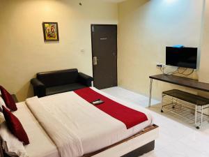 a bedroom with a bed and a desk and a television at Hotel Jagdish in Raipur