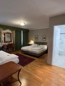 a bedroom with two beds and a table and a desk at Hotel Gösser Bräu in Wels