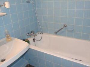 a blue tiled bathroom with a white tub and a sink at Appartement Lohf in Glücksburg