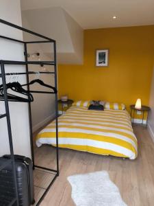 um quarto com uma cama com uma parede amarela em Appartement avec jardin plein sud ROUEN em Rouen
