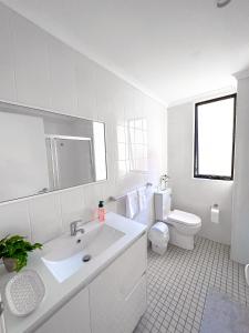 a white bathroom with a sink and a toilet at Convenient 2BR in Marrickville in Sydney