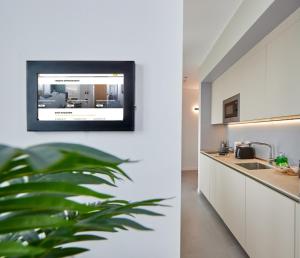 a kitchen with white cabinets and a tv on a wall at Gioia 55 in Milan