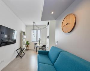 uma sala de estar com um sofá azul e um relógio na parede em Gioia 55 em Milão