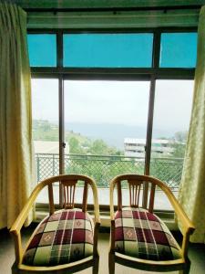 two chairs sitting in front of a large window at Bird's Nest in Bhurban